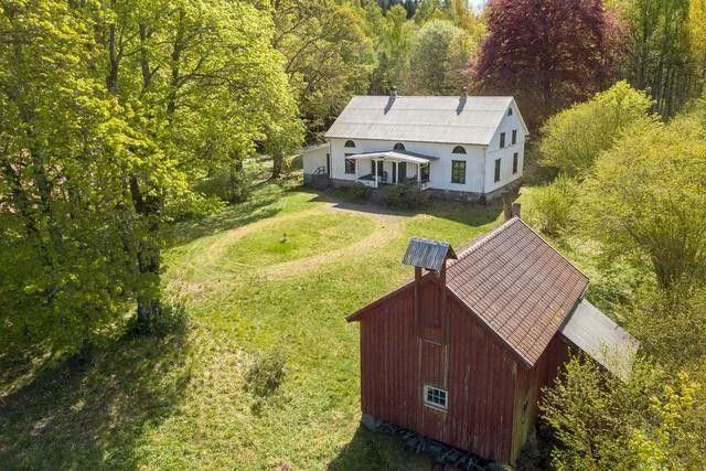 Aerial view of Norra Backen's white manor house, red outbuilding and woodland