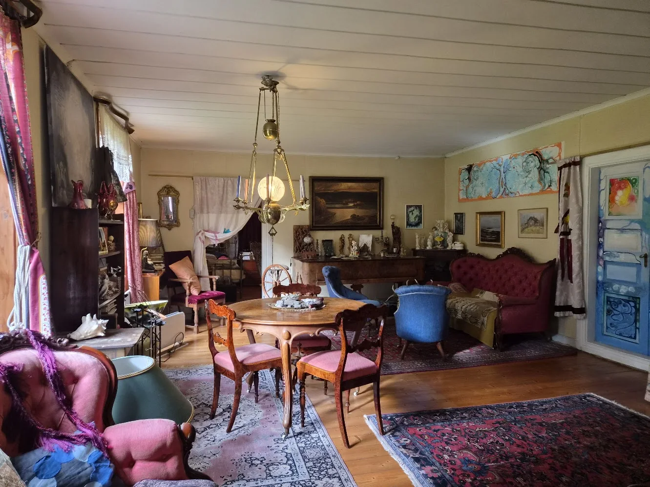 The eclectic sitting room with antique furniture, blue armchairs and painted doors